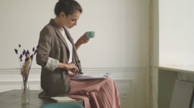 İyi görünümlü genç bir kadın içeride kahve içerken belgeleri tutuyor.