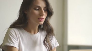 Güzel düşünen genç bir bayana yaklaşan kamera içeride dizüstü bilgisayar kullanıyor.