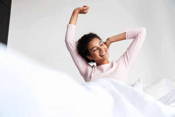 Sonriente hermosa joven africana sentada en la cama —  Fotos de Stock