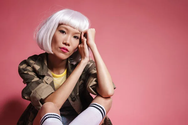 Imagen de chica asiática joven con peluca blanca sentada y mirando —  Fotos de Stock