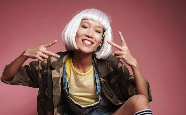 Imagem de menina asiática vestindo peruca branca sorrindo e gesticulando peac — Fotografia de Stock