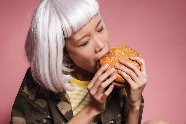 Imagem de jovem menina asiática em peruca branca se divertindo e comendo grande — Fotografia de Stock