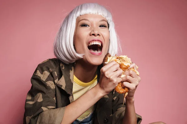 Wizerunek azjatyckiej dziewczyny w białej peruce krzyczącej i jedzącej duże b — Zdjęcie stockowe