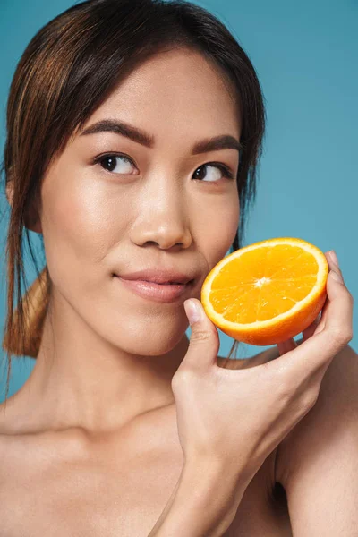 주황색을 들고 옆을 바라보고 있는 반쯤벌거벗은 아시아 여성의 사진 — 스톡 사진