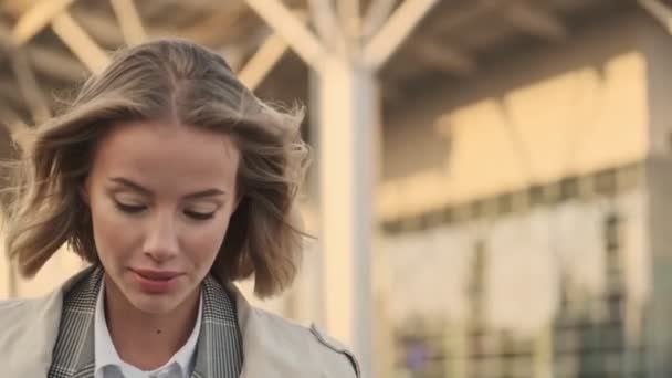 Glimlachende Blonde Zakenvrouw Jas Lopen Weg Kijken Luchthaven Parkeren Buiten — Stockvideo