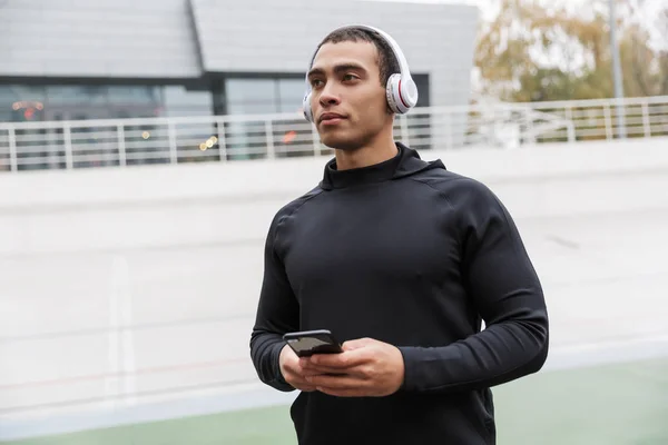 Foto de esportista atlético caucasiano usando fones de ouvido e celular — Fotografia de Stock