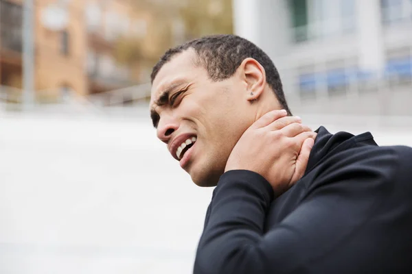 Foto de un infeliz deportista fuerte tocándose el cuello mientras hace ejercicio — Foto de Stock