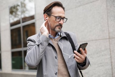 Cep telefonu ve kulaklık kullanan bir iş adamı görüntüsü