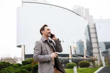 Gülümseyen yakışıklı iş adamının cep telefonuyla konuşması.