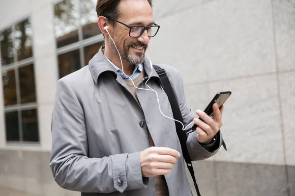 Εικόνα χαρούμενου επιχειρηματία που χρησιμοποιεί κινητά και ακουστικά — Φωτογραφία Αρχείου
