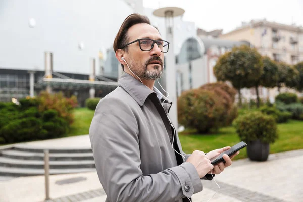 Imagen de un hombre de negocios guapo usando teléfono celular y auriculares — Foto de Stock