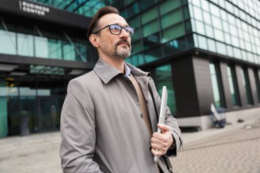 Dizüstü bilgisayarı tutan yakışıklı iş adamının görüntüsü