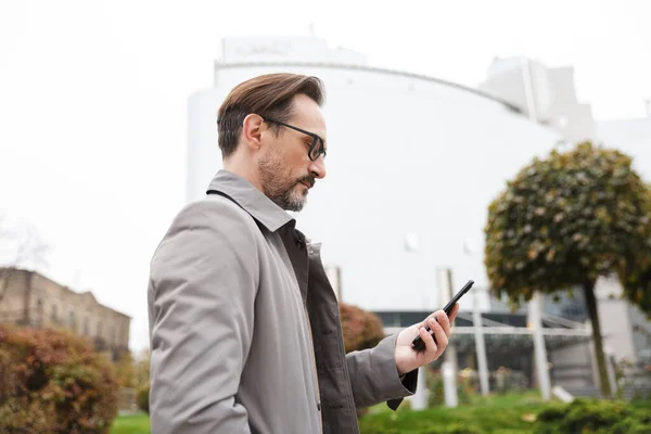 Imagen de hombre de negocios concentrado en anteojos usando celular — Foto de Stock