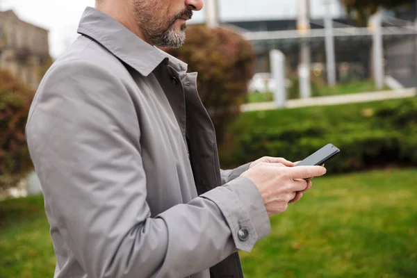 Gesneden beeld van volwassen zakenman met behulp van mobiele telefoon — Stockfoto