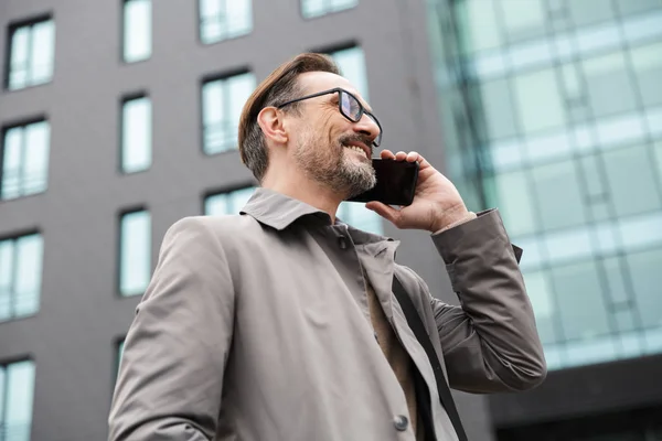 Imagen de un hombre de negocios sonriente hablando por teléfono celular mientras está de pie — Foto de Stock