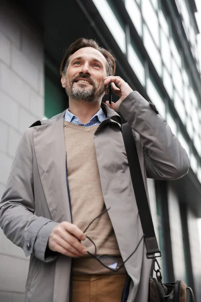 Immagine di maturo uomo d'affari sorridente che parla sul cellulare mentre cammina — Foto Stock