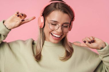 Sarışın mutlu kadının portresi. Kulaklık takıp dans ediyor.