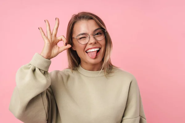 Portrait of young smiling woman winking and gesturing ok sign — Stock Photo, Image