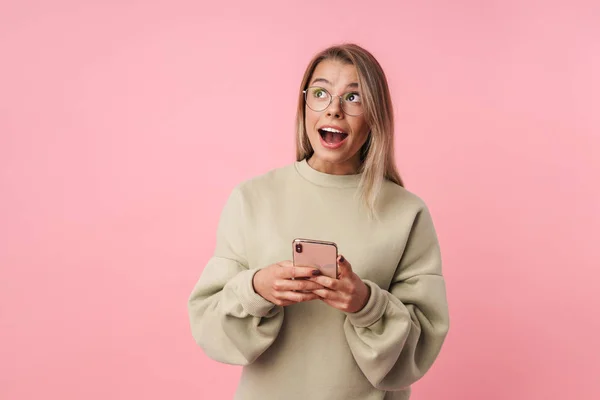 Portrait of young shocked woman using cellphone and looking upward — Stock Photo, Image