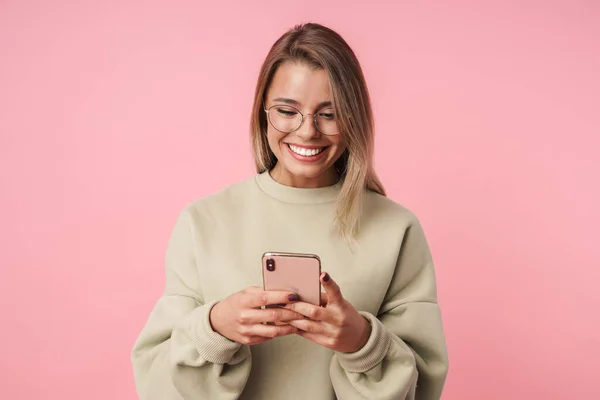 Портрет приємної смішної жінки в окулярах використовуючи мобільний телефон і посміхаючись — стокове фото