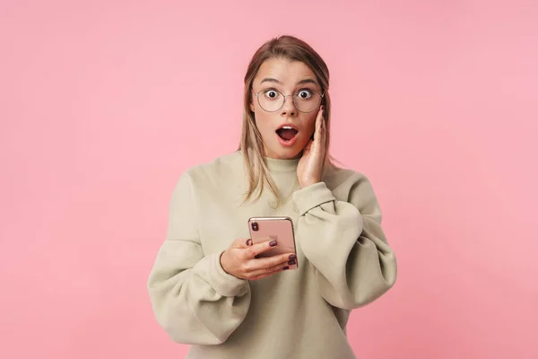 Портрет молодой шокированной женщины, использующей мобильный телефон и смотрящей в камеру — стоковое фото