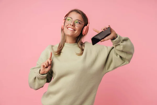Portrait of happy woman using headphones while pointing finger upward — Stock Photo, Image