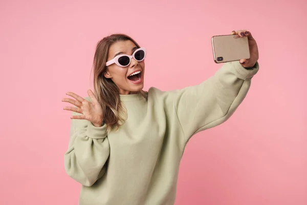 Retrato de mujer excitada agradable usando el teléfono celular y la mano ondulante — Foto de Stock