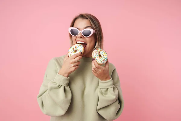 Ritratto di bella donna felice in occhiali da sole mangiare ciambelle — Foto Stock