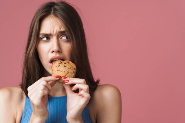 Image of young girl frowning while eating biscuits and looking a