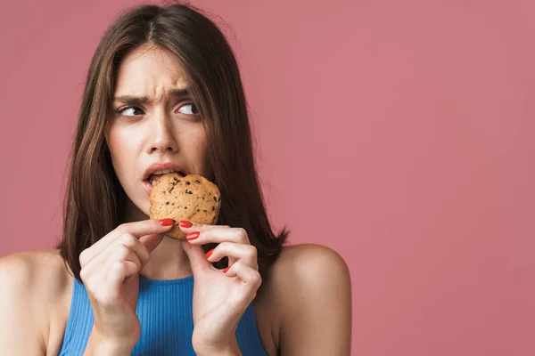 Image of young girl frowning while eating biscuits and looking a — ストック写真