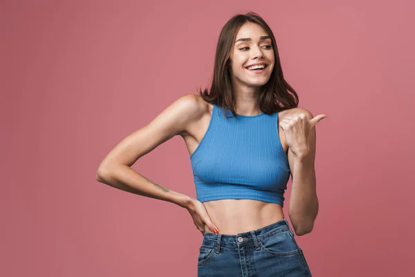 Image of young brunette woman smiling and pointing finger aside — Stok fotoğraf