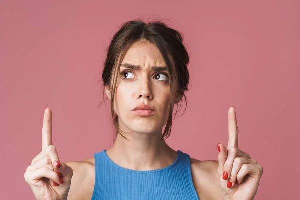 Image of young brunette woman pointing fingers upwards at copysp — 图库照片