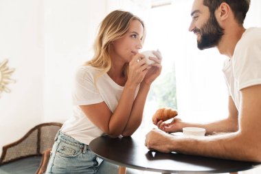 Positive loving couple indoors drinking coffee.