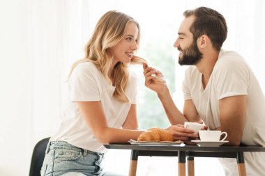 Positive loving couple indoors drinking coffee.