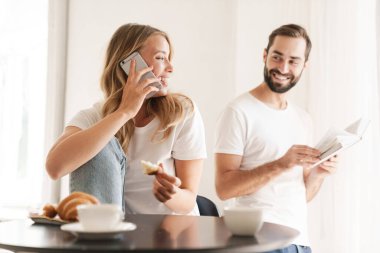 Woman talking by phone while husband reading book