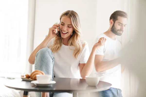 Mujer hablando por teléfono mientras su marido lee el libro — Foto de Stock