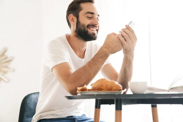 Man indoors at home have a breakfast using mobile phone. — Stock Photo, Image