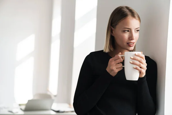 Blonde business woman in office indoors drinking hot tea. — Stock Fotó