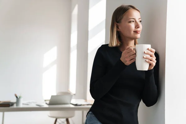 Rubia mujer de negocios en la oficina en interiores beber té caliente . — Foto de Stock