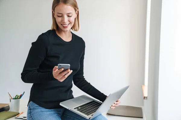 Mulher no escritório com computador portátil e telefone móvel . — Fotografia de Stock