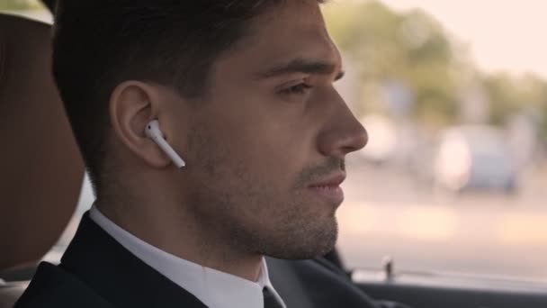 Kulaklık Takıp Arabada Otururken Gözlerini Kaçıran Yakışıklı Adamının Yan Görüntüsü — Stok video