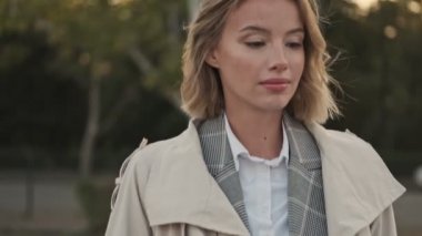 Kapalı alanda havaalanının yakınındaki otoparkta yürürken ve otururken gülümseyen sarışın iş kadını görüntüsü.