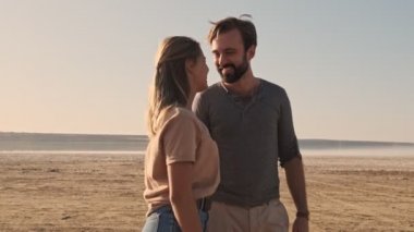 Genç ve güzel bir çift yazın göl kenarında yürüyor ve sarılıyorlar.