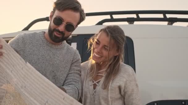 一对年轻夫妇站在湖边的汽车旁边 手里拿着一张地图 — 图库视频影像