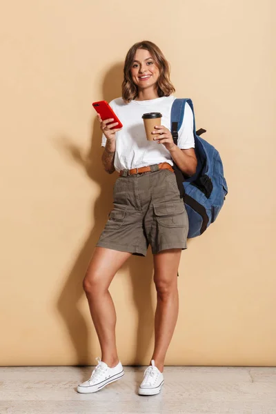 Image Pleased Student Girl Holding Takeaway Coffee Cup Smartphone Isolated — Stockfoto