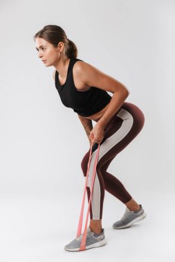 Spor giyimli bir kadının spor yaparken beyaz arka planda izole edilmiş genişletici ekipmanlarla görüntüsü