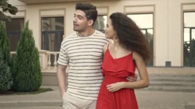 Gündelik giysiler içinde mutlu bir beyaz çift şehirde yürürken gülümsüyor ve sarılıyor.