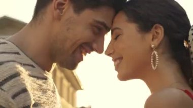 Şehir caddesinde yürürken birbirlerine bakan ve yaz kıyafetleri içinde gülümseyen güzel bir çiftin yakın çekimi.