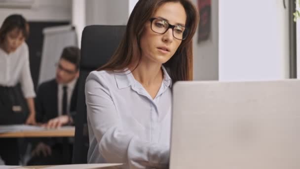 严肃的女商人坐在办公室时戴着眼镜 带着文件和手提电脑 — 图库视频影像