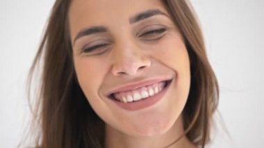 Neşeli, güzel amigo kadının gri arka planda poz verip kameraya bakışının yakın görüntüsü.